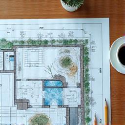 A detailed landscape design blueprint on a wooden table.